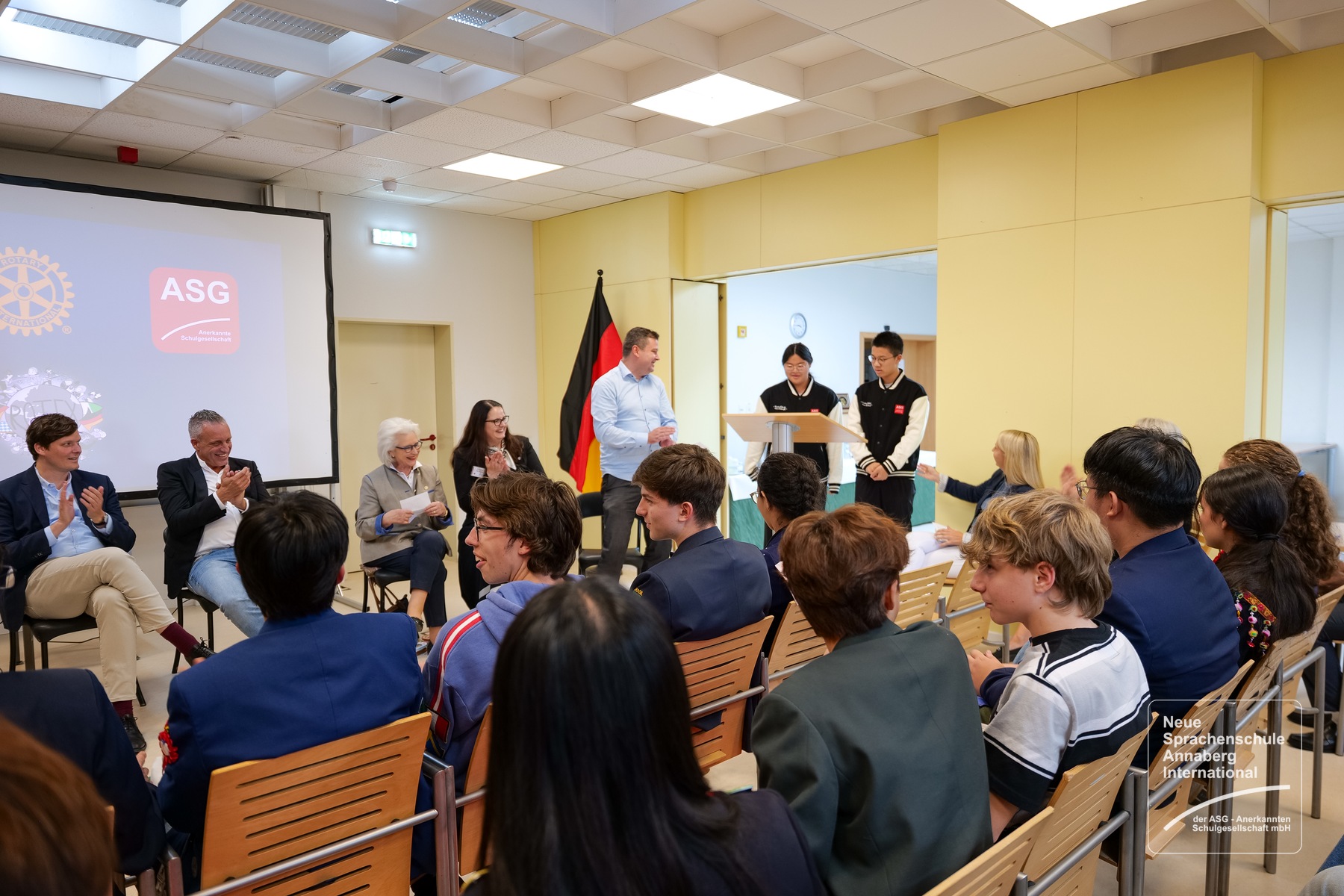 Schülerinnen und Schüler unseres Abiturprojekts begrüßen die Gäste am Rednerpult